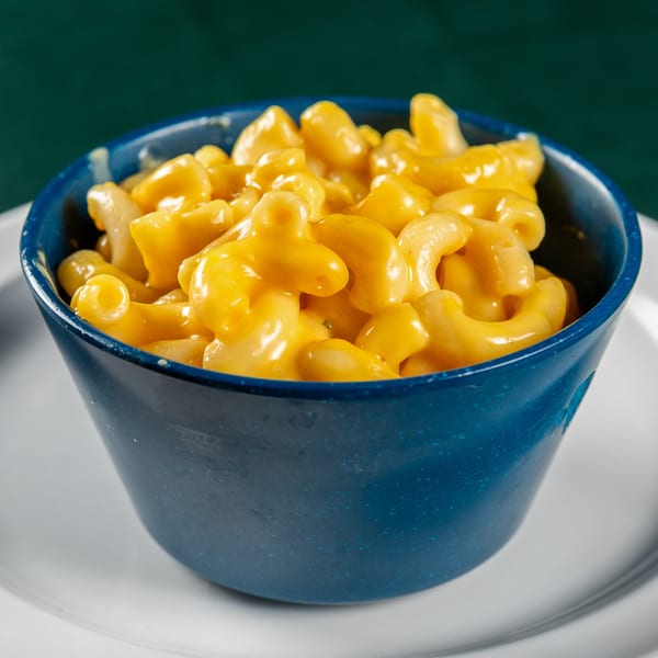 A blue bowl filled with creamy, golden macaroni and cheese, a classic Ace's BBQ side dish.