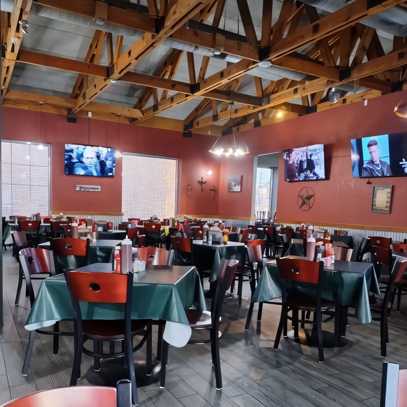 Interior of Ace's BBQ with red walls, exposed wooden beams, and tables set with red and green tablecloths.