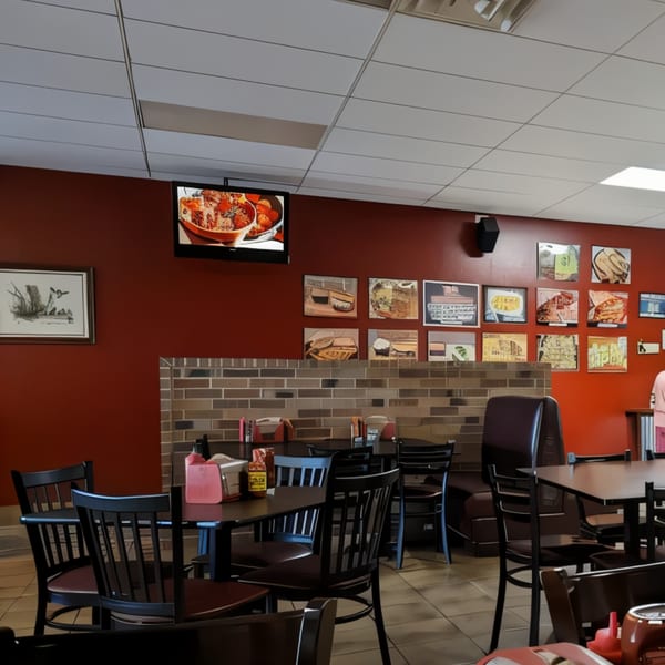Interior of Ace's BBQ with red walls, brick accents, black tables, chairs, and food art.