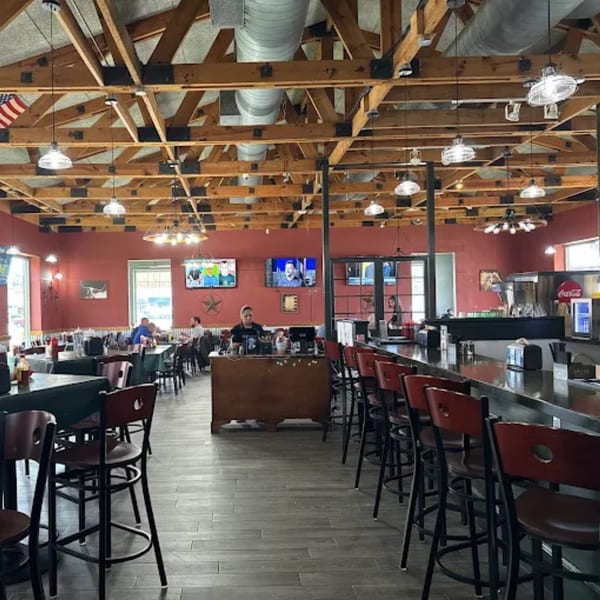 Spacious Ace's BBQ dining room with red walls, exposed wooden beams, bar seating, and patrons.
