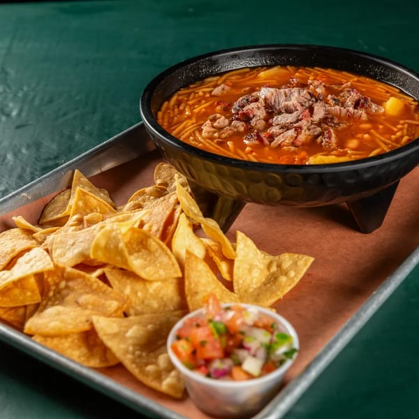 Ace's BBQ fideo soup with brisket, served with tortilla chips and salsa on a metal tray.