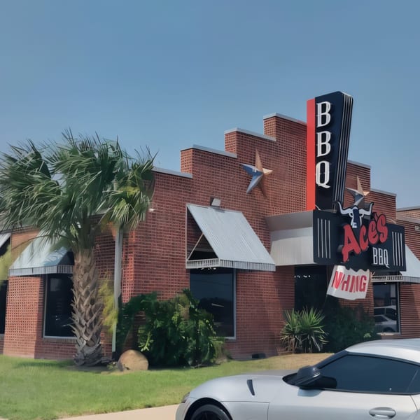 Ace's BBQ restaurant exterior with a large sign, brick facade, palm tree, and a silver car.